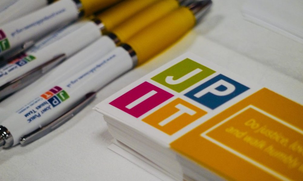 Pens and a stack of business cards for JPIT on a table