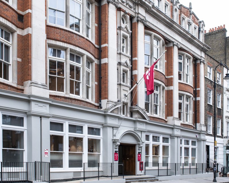 Street view of Methodist Church House’s red‑brick Edwardian façade flying a the Methodist Church flag.